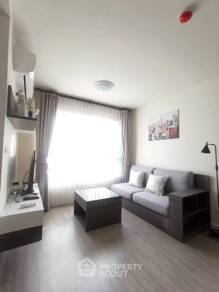 Modern living room with sleek furniture and large window, perfect for cozy relaxation.