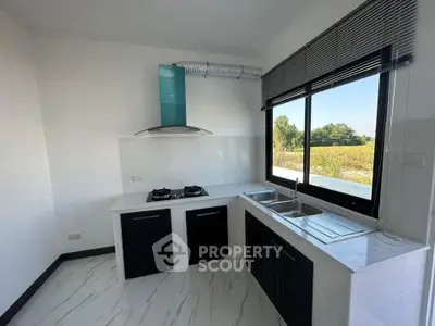 Modern kitchen with sleek black cabinets, dual gas stove, and large window offering scenic views.