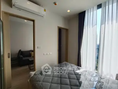Modern bedroom with natural light and city view, featuring sleek design and comfortable furnishings.