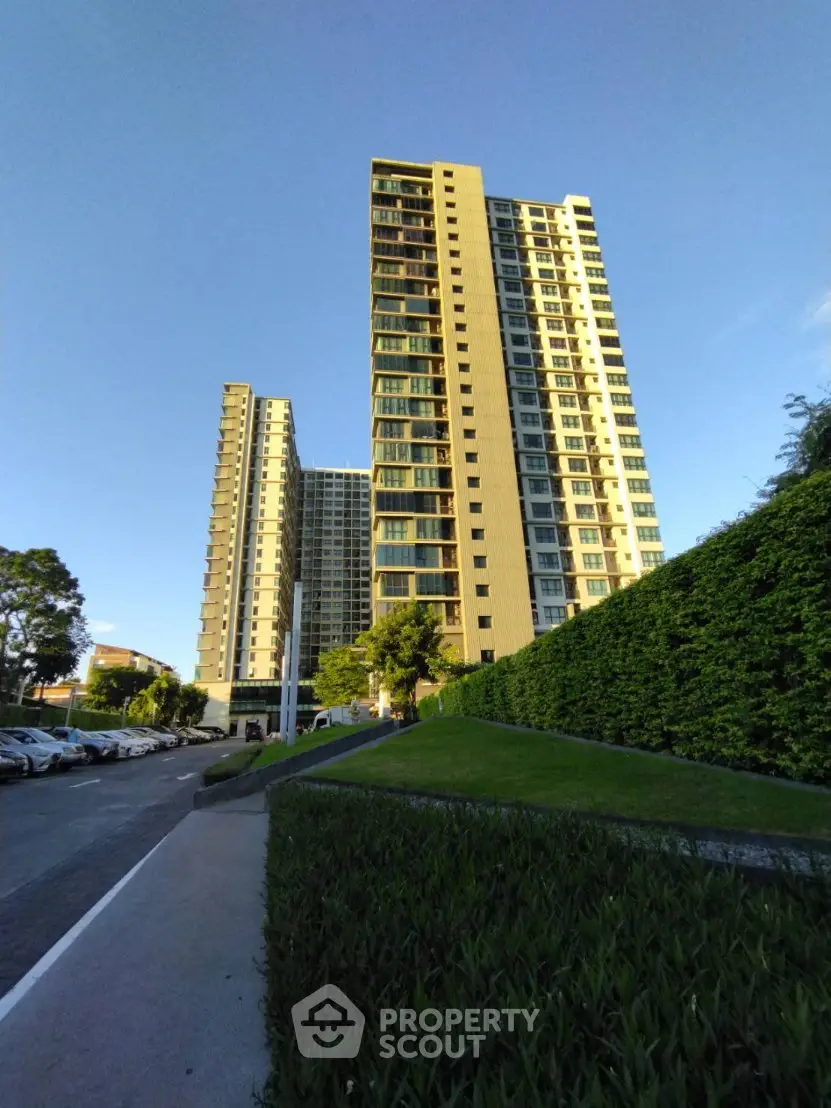 Modern high-rise residential building with lush greenery and clear blue sky.