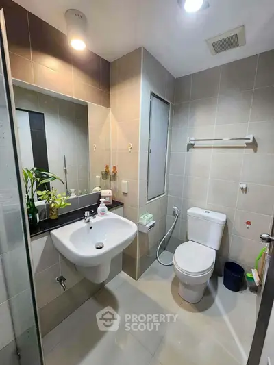 Modern bathroom with sleek fixtures and neutral tiles, featuring a large mirror and contemporary design.