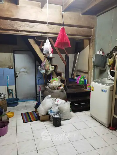 Rustic storage area with staircase and washing machine in a vintage home setting.