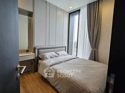 Modern bedroom with cozy bed and stylish decor, featuring large windows and natural light.