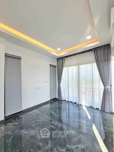 Spacious modern living room with marble flooring and large windows for natural light.
