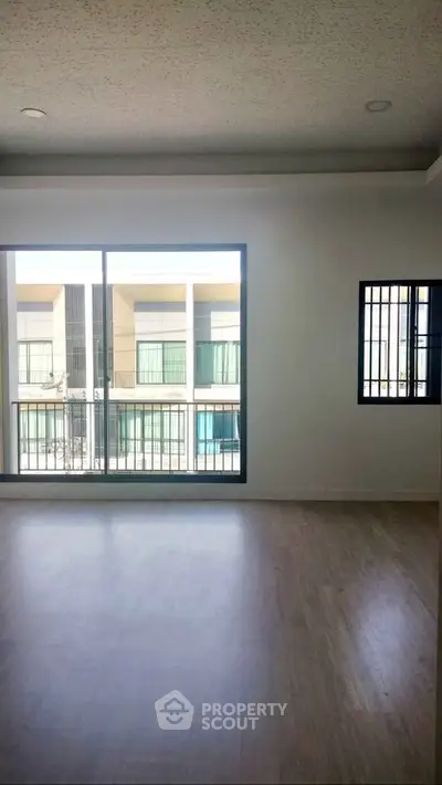 Spacious modern living room with large windows and wood flooring, offering a bright and airy atmosphere.