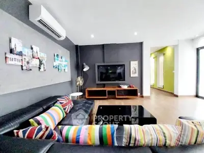Spacious modern living room with colorful decor and sleek black furniture