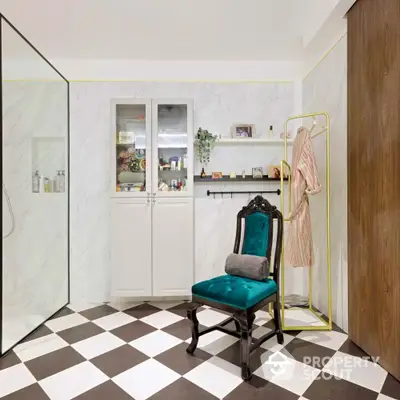 Elegant bathroom with checkered floor, luxurious chair, and glass shower enclosure.