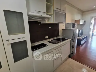 Modern kitchen with sleek cabinetry and appliances in a cozy apartment setting.