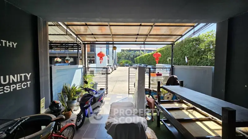 Spacious covered parking area with motorbikes and outdoor seating, ideal for urban living.