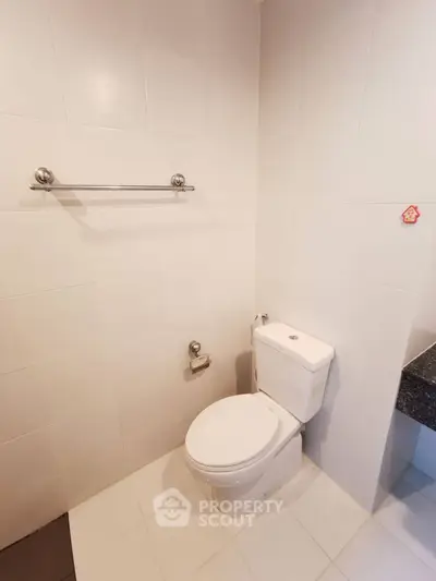 Modern bathroom with sleek white tiles and contemporary toilet design.