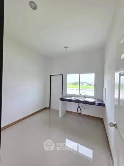 Bright kitchen with sleek countertop and large window offering scenic views.