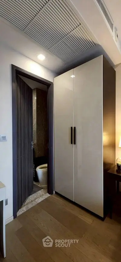 Modern apartment interior with sleek wardrobe and bathroom entrance, featuring elegant wood flooring and contemporary design.