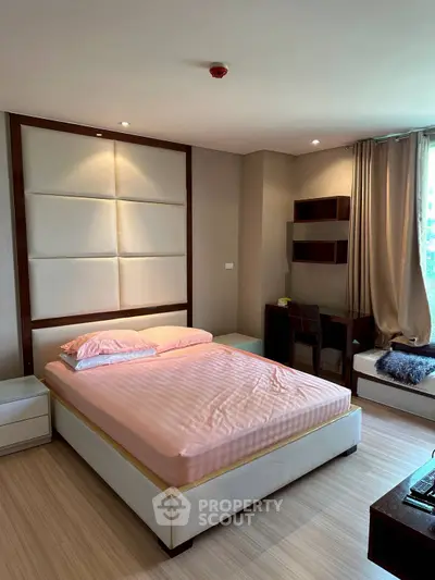 Spacious bedroom with modern decor and natural light, featuring a comfortable bed and stylish workspace.