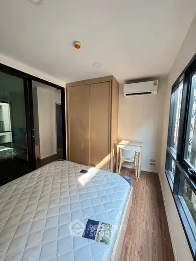 Modern bedroom with large windows and wooden flooring in a cozy apartment