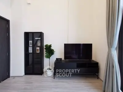 Modern living room with sleek black furniture and large window curtains.