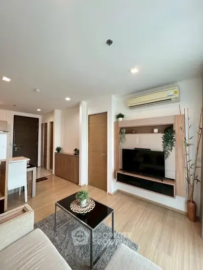 Modern living room with sleek design, featuring a wall-mounted TV, air conditioning, and stylish decor.