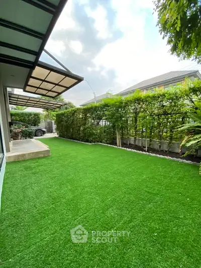 Spacious backyard with lush green lawn and modern awning, perfect for outdoor relaxation.