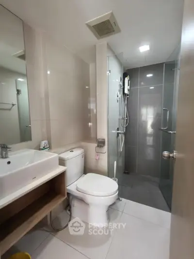 Modern bathroom with sleek design, featuring a glass shower enclosure and contemporary fixtures.