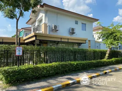 Modern two-story house with lush greenery and air conditioning units, ideal suburban living.