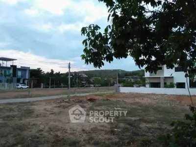 Spacious residential plot with scenic views and nearby modern homes.