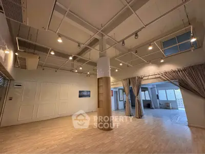 Spacious open-plan interior with modern lighting and wooden flooring, ideal for versatile living or office space.