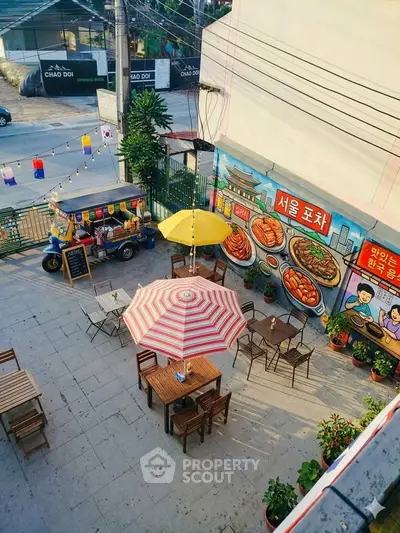 Charming outdoor dining area with colorful umbrellas and street art, perfect for a vibrant urban lifestyle.