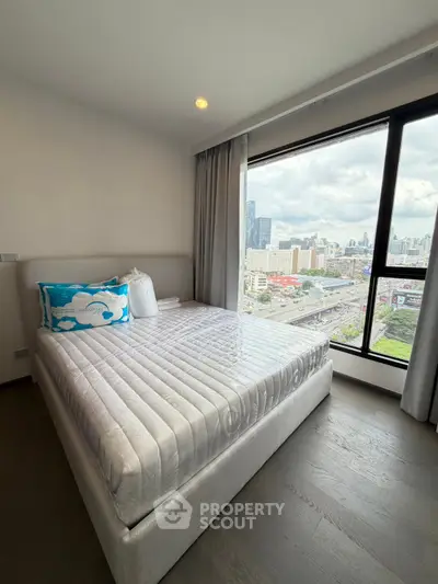 Modern bedroom with large window offering stunning city view, featuring a cozy bed and elegant decor.