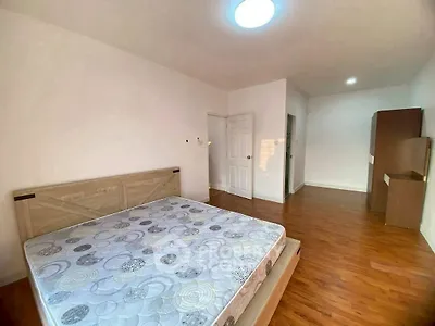 Spacious bedroom with wooden flooring and natural light, featuring a modern bed and ample storage space.