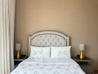 Elegant bedroom with plush headboard and stylish lamps, perfect for a cozy retreat.