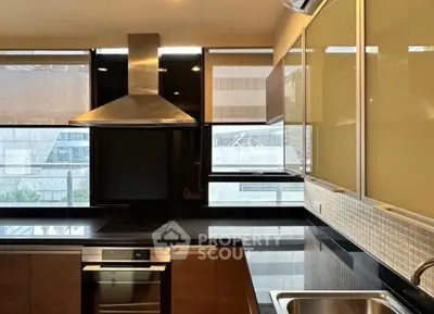 Modern kitchen with sleek design, featuring stainless steel appliances and large windows with city view.