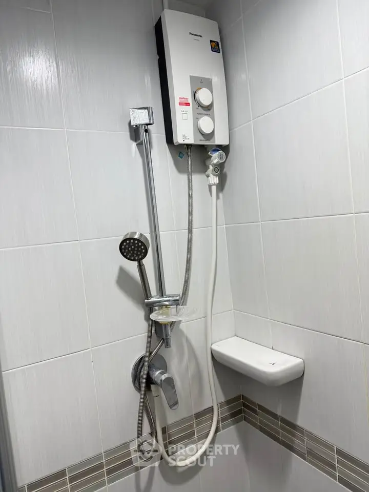 Modern bathroom with sleek shower and water heater, featuring elegant tile design.
