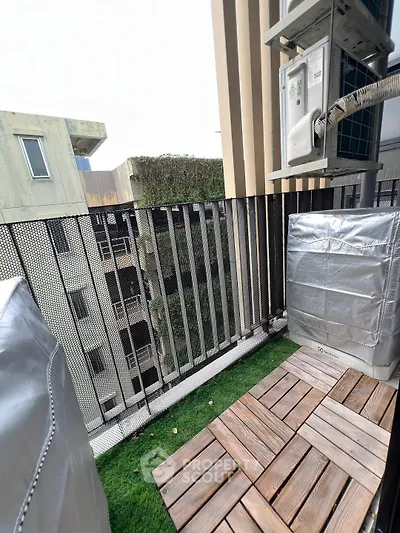 Charming small balcony with artificial grass and wooden decking, perfect for urban relaxation.