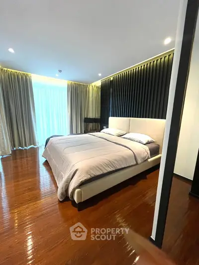 Luxurious bedroom with modern design and elegant lighting, featuring a large bed and polished wooden floors.