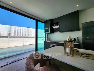 Modern kitchen with pool view, sleek cabinetry, and cozy dining area.