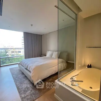 Luxurious bedroom with modern ensuite bathtub and large window view.