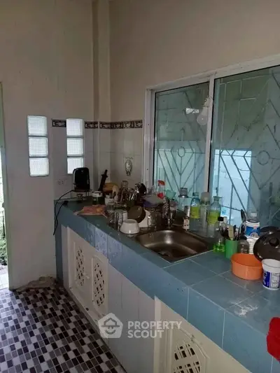 Cozy kitchen with tiled countertops and window view, featuring essential appliances and ample storage space.