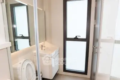 Modern bathroom with sleek fixtures and large frosted window for natural light.