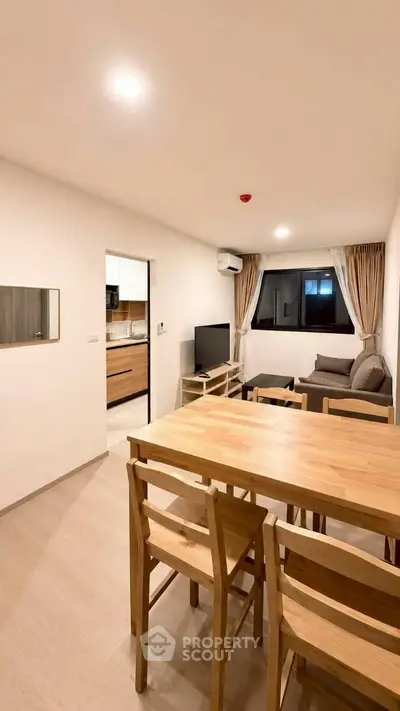 Modern living room with wooden dining set and cozy seating area, open layout to kitchen.