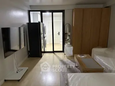 Modern living room with sleek TV, washer-dryer, and stylish furniture in open layout.
