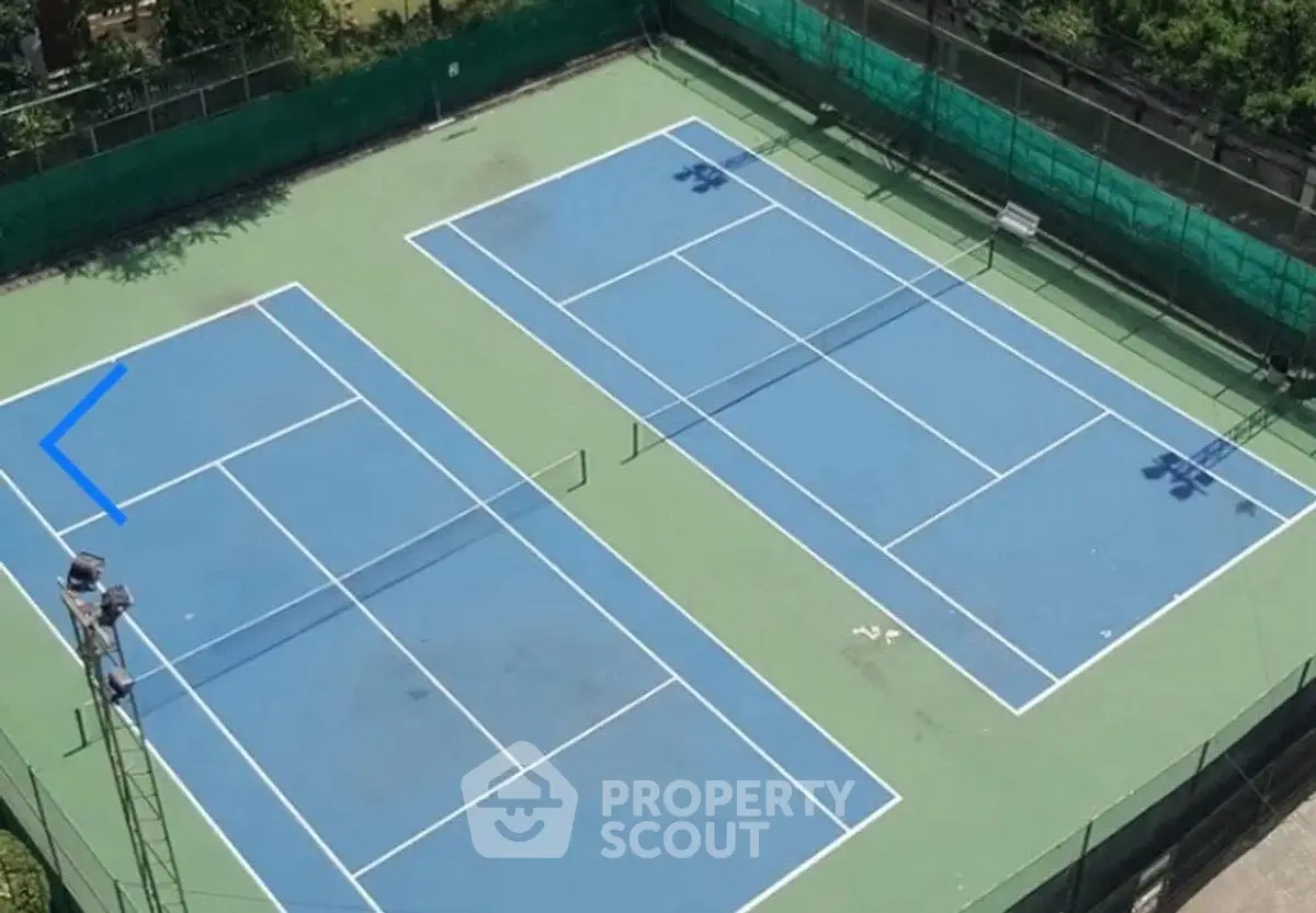 Aerial view of two outdoor tennis courts in a residential complex.