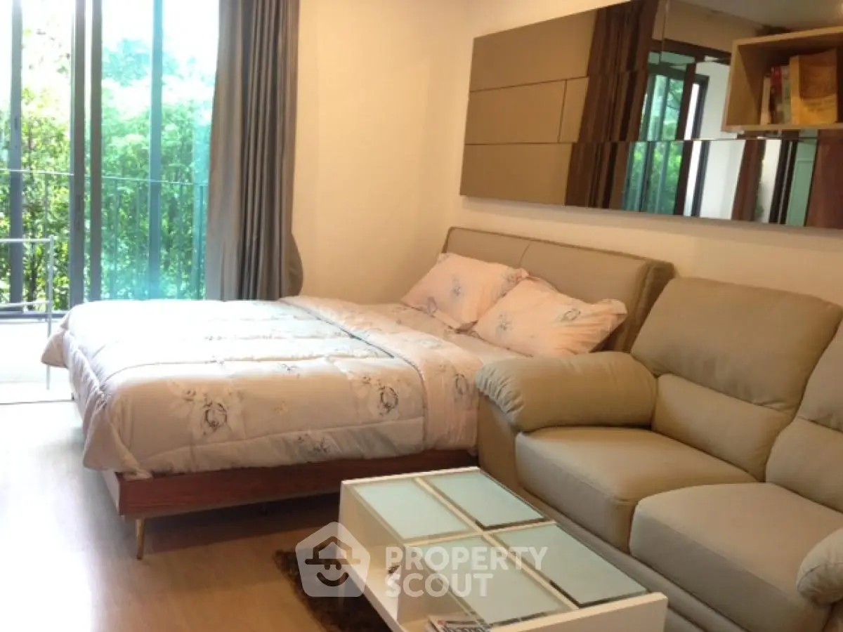 Cozy bedroom with modern decor and balcony view, perfect for relaxation.