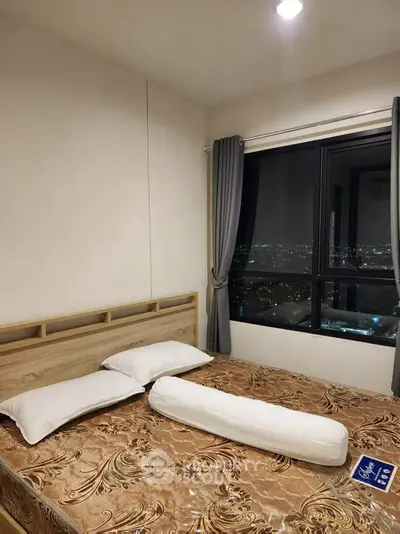 Cozy bedroom with city view, featuring modern decor and large window for natural light.