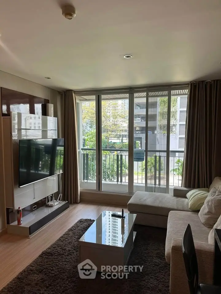 Spacious living room with large windows and modern decor in a high-rise apartment.