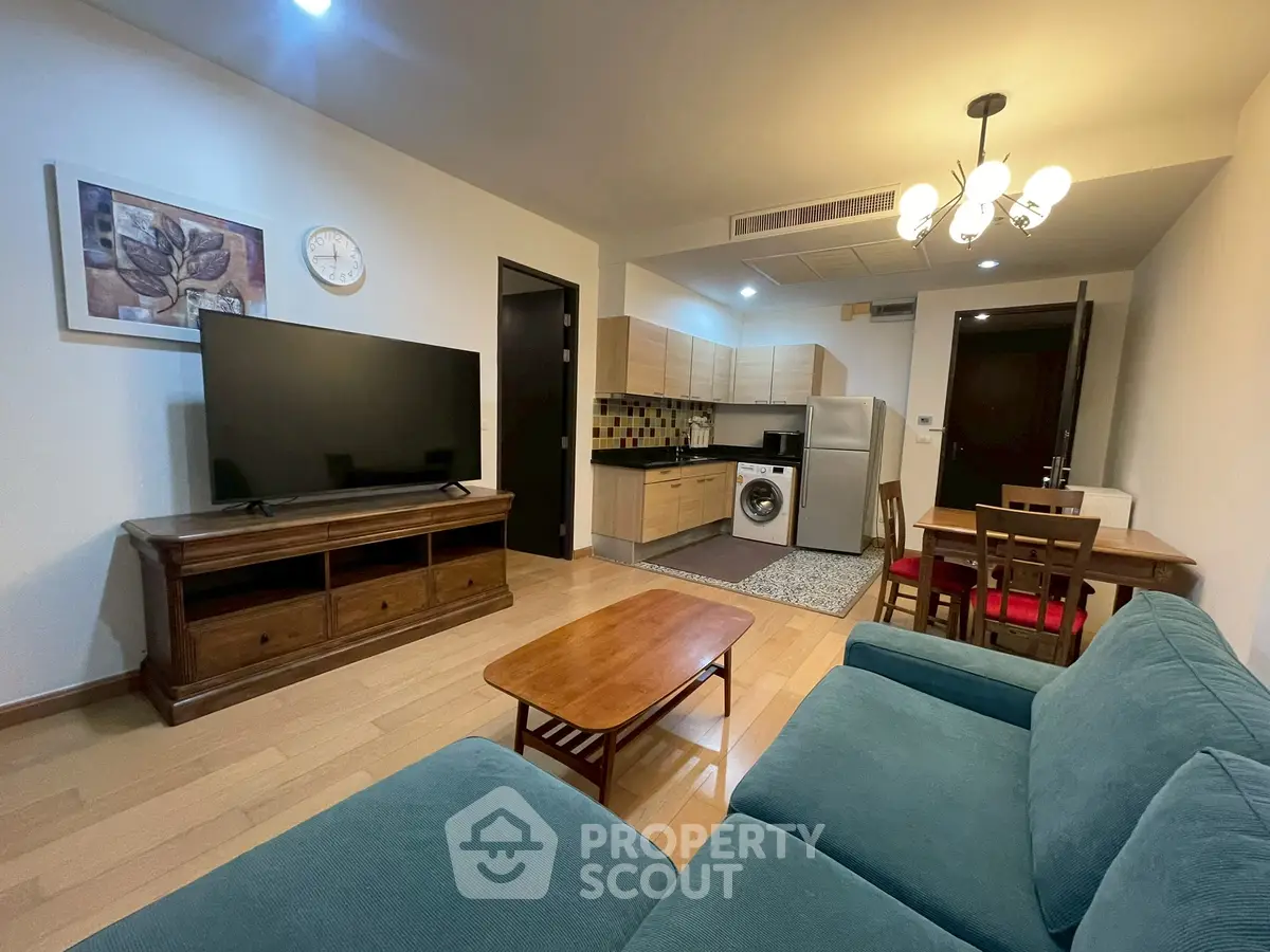 Cozy living room with modern kitchen and dining area, featuring a washing machine and stylish decor.