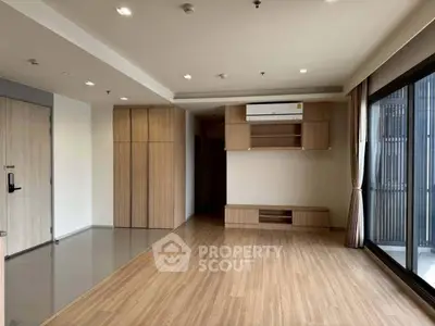 Spacious modern living room with wooden flooring and large windows in a contemporary apartment.
