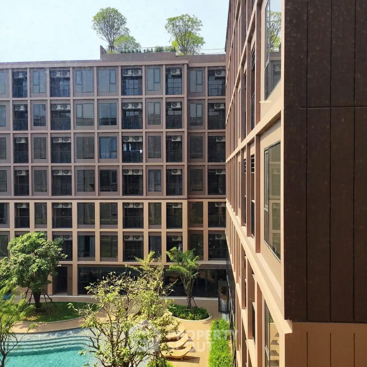Modern apartment building with pool and lush greenery, perfect for urban living.
