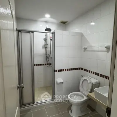 Modern bathroom with shower and toilet in a tiled setting