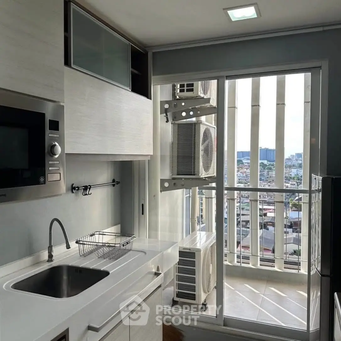 Modern kitchen with sleek cabinetry and city view from balcony, featuring built-in microwave and compact design.