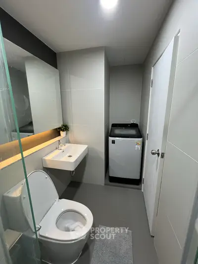 Modern bathroom with sleek design and washing machine, ideal for compact living spaces.