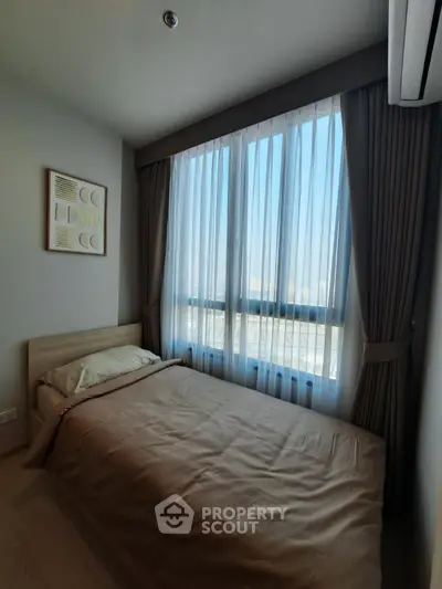 Cozy bedroom with large window and modern decor in a high-rise apartment